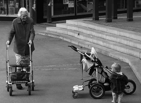 &Auml;ltere Dame mit Gehhilf und Kleinkind neben Kinderwagen. 